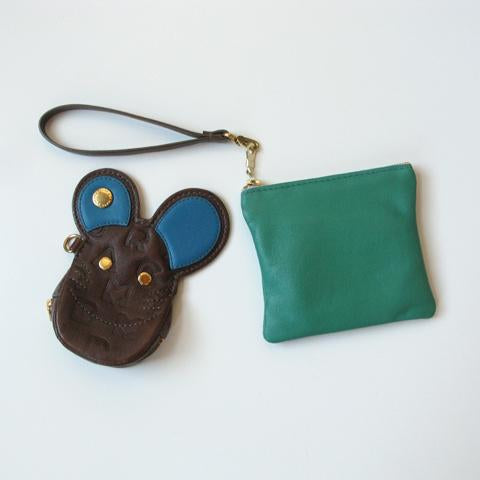 Brown leather mouse coin purse with blue ears and gold accents on wrist strap, next to a teal zipper pouch