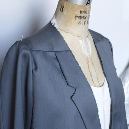 Slate blue jacket with notched lapels and slightly voluminous sleeves on a dress form
