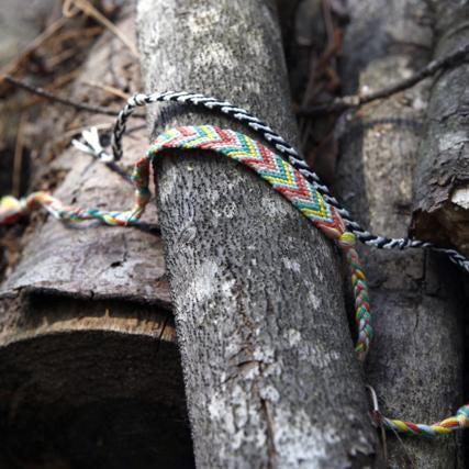 Colorful chevron friendship bracelets tied around a weathered tree branch