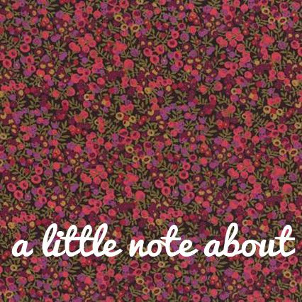 Dense floral print in pink and magenta on dark green background with white script text reading "a little note about