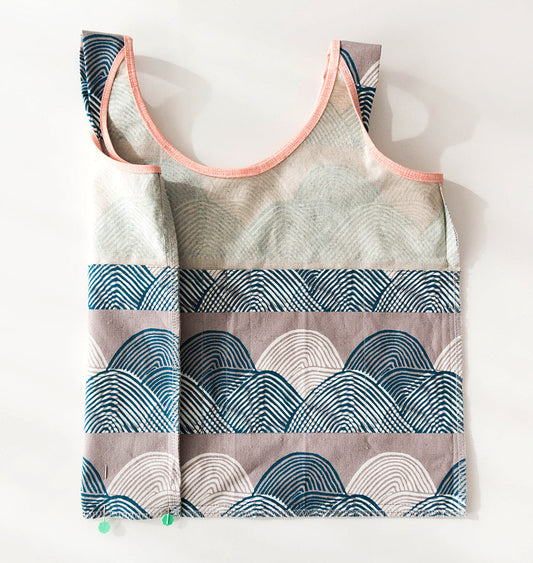 Inside-out Stowe Bag showing interior pockets in mixed wave print fabrics, teal, gray, and mauve with pink bias tape handles