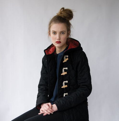 Person wearing black quilted duffle coat with red lining, wooden toggle closures, and hood over navy top, RTW inspiration