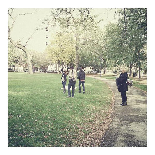 People walking through a tree-lined park during behind-the-scenes fashion photography shoot