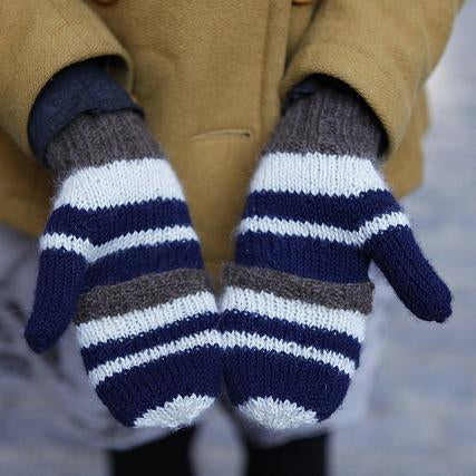 Pair of hand-knit striped mitts in navy, white, and brown with ribbed cuffs, worn with a mustard yellow peacoat
