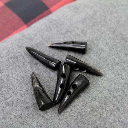 Black horn toggle buttons on gray wool fabric with red buffalo plaid in the background
