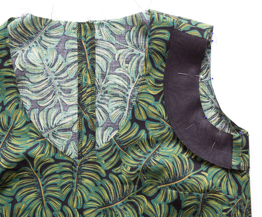 Hadley Top armhole facing pinned in place on charcoal and green leaf-print fabric, ready to sew