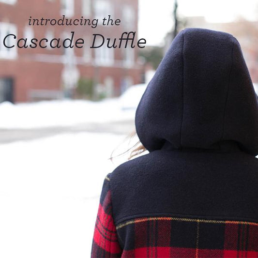 Cascade Duffle Coat intro graphic showing navy wool hood and yoke with red plaid body and sleeves, worn in a snowy setting