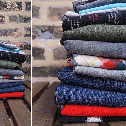 Stacked folded knit fabrics in stripes, prints, and solids in black, blue, gray, red, and green