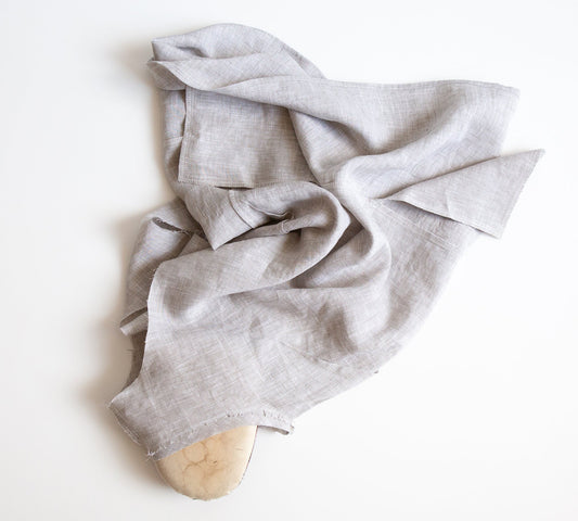 Uniform Tunic in natural linen draped over a tailor's ham on white surface, showing armhole bias facing during construction
