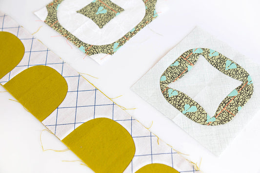 Needle-turn applique in Carolyn Friedlander fabric: mustard shapes on grid and medallion blocks on white background
