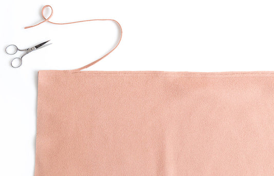 Yates Coat blush wool coating fabric with scissors and thread, grading the waistline seam