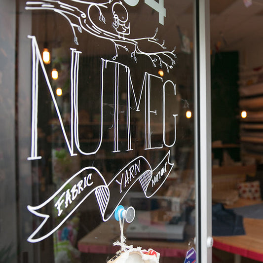 Nutmeg shop window with hand-lettered sign reading Fabric, Yarn, Notions in Nashville