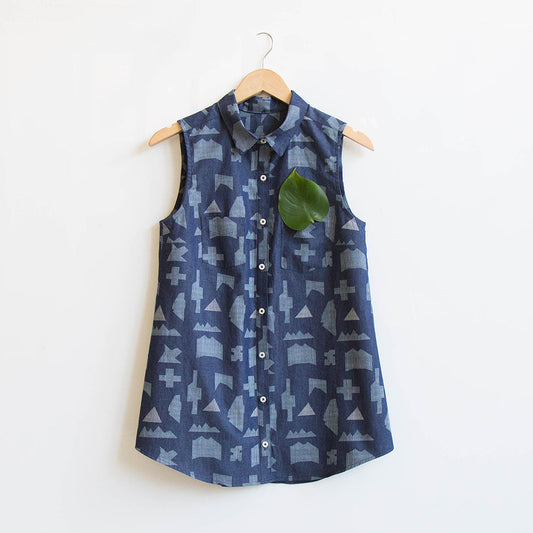 Sleeveless Alder Shirtdress in navy geometric print denim, shortened to tunic length, on a wooden hanger with leaf accent