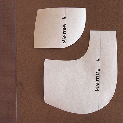 Maritime Shorts pattern pieces showing concave and convex pocket curve pieces in size 6, on a brown worktable