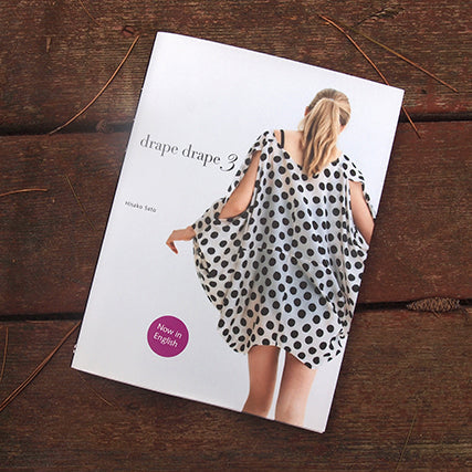 Drape Drape 3 sewing book by Hirako Sato on a wood surface, cover showing a model in a black and white polka dot draped tunic