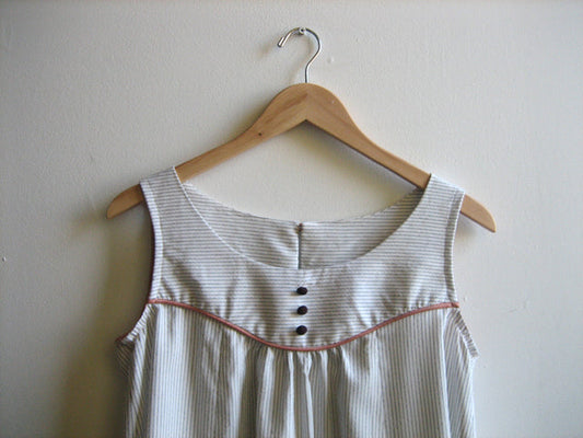 Sleeveless striped nightgown with button placket and coral piping trim at yoke seam on wooden hanger