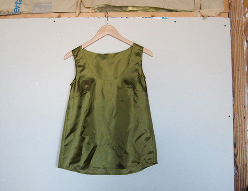 Army green silk habotai sleeveless tank top draped prototype on wooden hanger against white backdrop