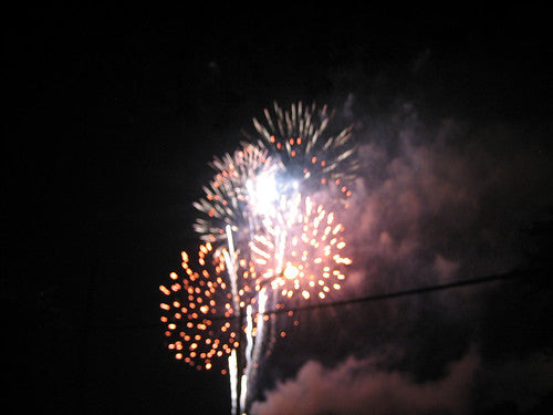 Fireworks bursting in the night sky in shades of gold, orange, and white against a dark background