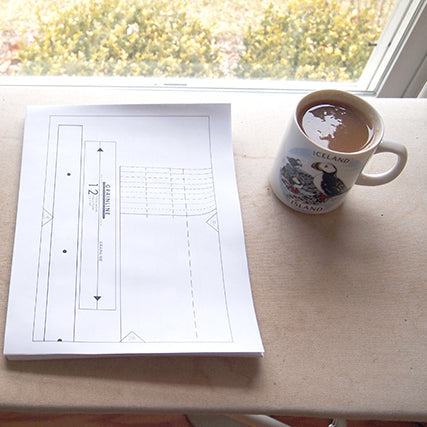 Printed Grainline Studio sewing pattern pieces on ironing board next to an Iceland souvenir mug of tea