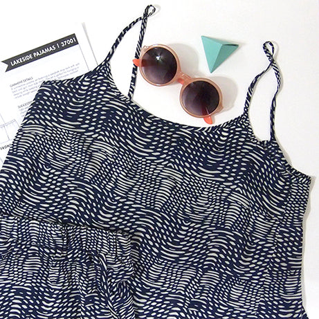 Lakeside Pajamas camisole in navy wave print flat lay with pattern envelope, coral sunglasses, and a teal geometric trinket