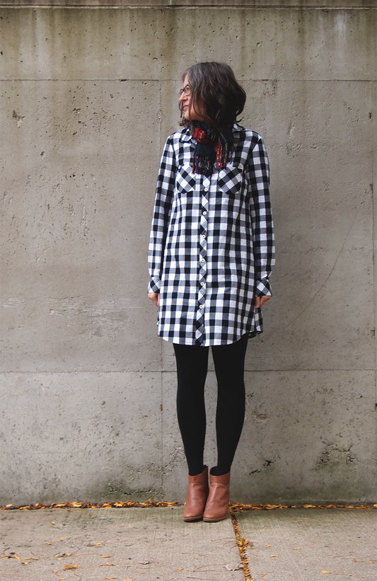 Alder Archer combo in black and white gingham, worn with black tights and cognac boots against concrete wall