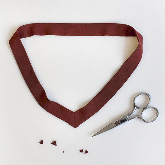 Burgundy V-neck band with sewn center seam, fabric scissors, and clipped seam points for Lark V-neck neckline finishing