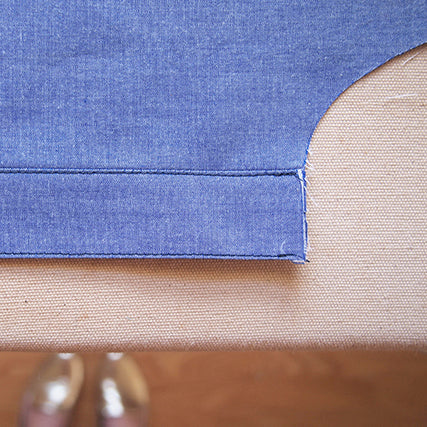 Close-up of a blue chambray Archer Button-Up button band folded and topstitched, showing the finished edge on a work surface