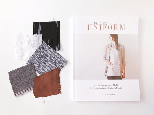 Knit and Sew Uniform book beside fabric swatches in black, white, gray stripe, gray linen, and rust for the Uniform Tunic