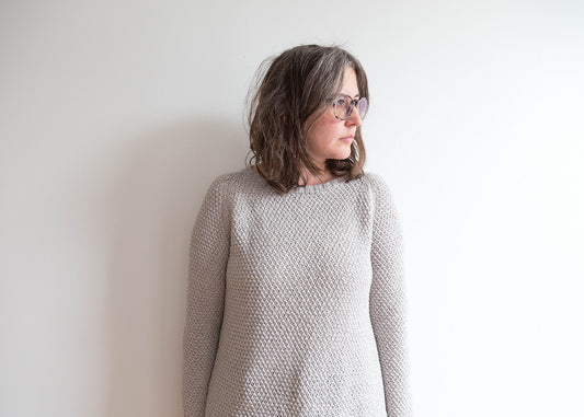 Martine Sweater by Julie Hoover in gray textured knit, crew neckline and long sleeves, modeled against a white wall"