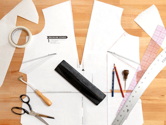 Augusta Shirt & Dress printed pattern pieces with scissors, tracing wheel, pencils, awl, rulers, pattern weight, and tape