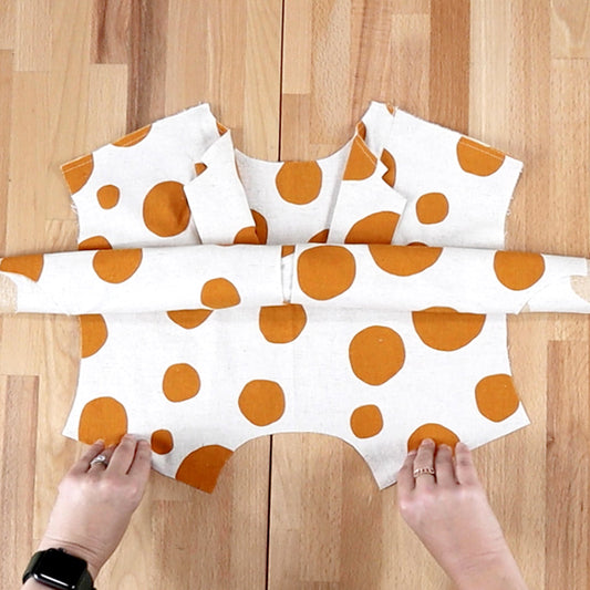 Augusta Shirt & Dress in cream linen with orange polka dots, showing yoke burrito method assembly, hands flat on wood table