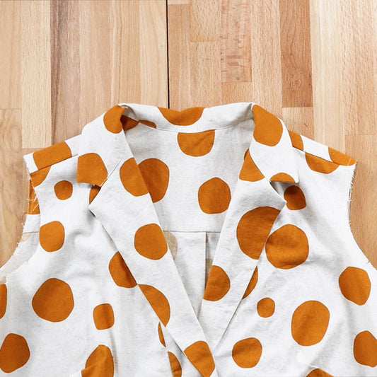 Augusta Shirt in cream linen with orange polka dots, showing collar assembly and attachment detail on wood table