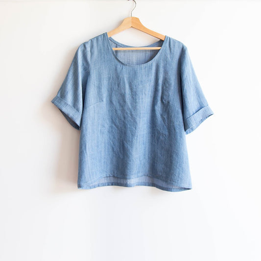 Scout Tee in light blue chambray with cuffed elbow-length sleeves on wooden hanger