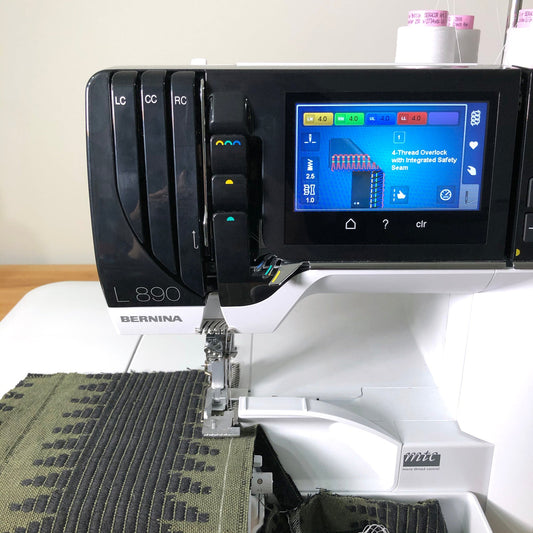 Bernina L890 serger with touchscreen showing 4-thread overlock setting, sewing olive and black jacquard fabric