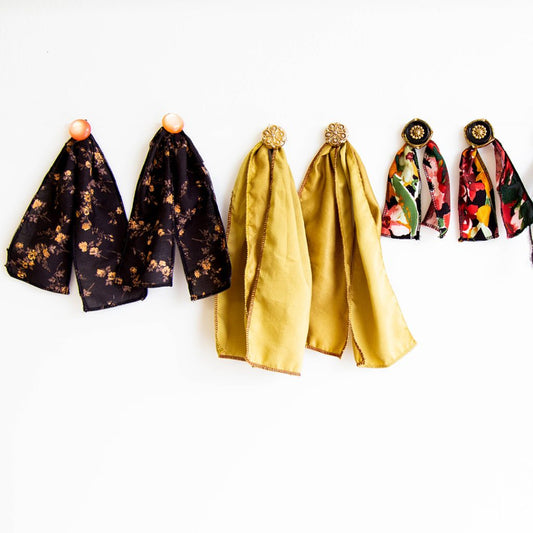 DIY earring tutorial: three pairs of fabric scrap earrings with vintage buttons, in black floral, gold, and colorful floral