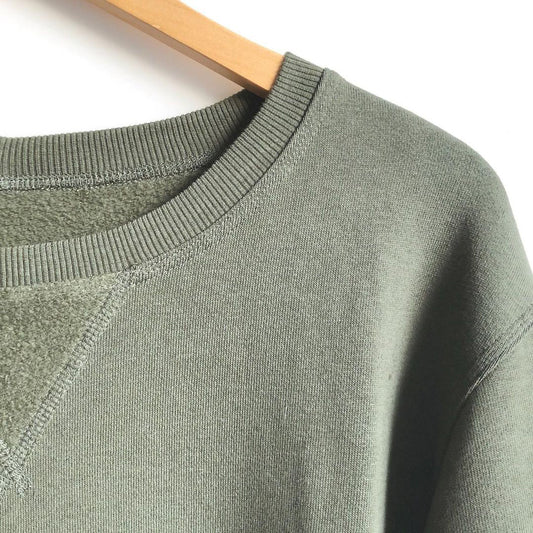 Sage green sweatshirt with ribbed crewneck and set-in triangle seam detail, on wooden hanger