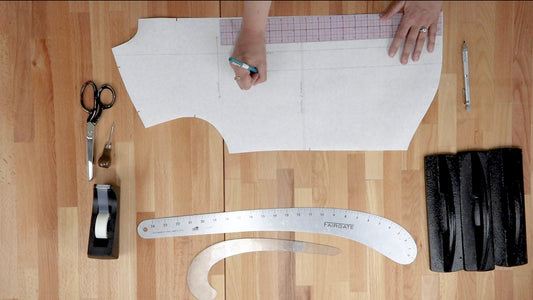 Hands marking Archer Button Up pattern pieces with Fairgate ruler, French curve, scissors, awl, pattern weights, and tape