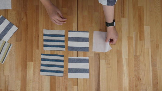 Striped fabric swatches with applied interfacing on wood table, demonstrating interfacing selection for the Archer Button Up