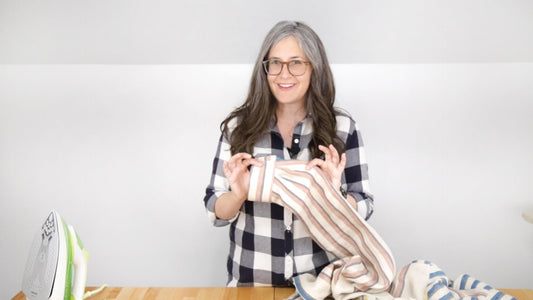Person wearing navy gingham Archer Button Up, demonstrating cuff attachment with a striped fabric sleeve on wood table
