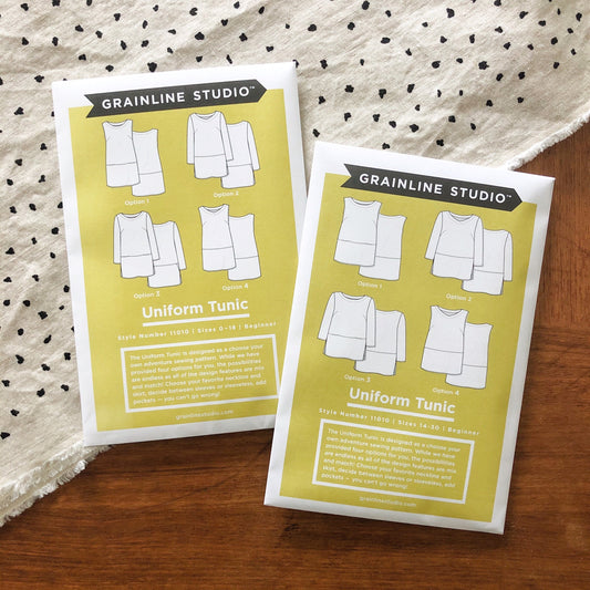 Two Grainline Studio Uniform Tunic pattern envelopes, sizes 0-18 and 14-30, showing four design options on yellow background