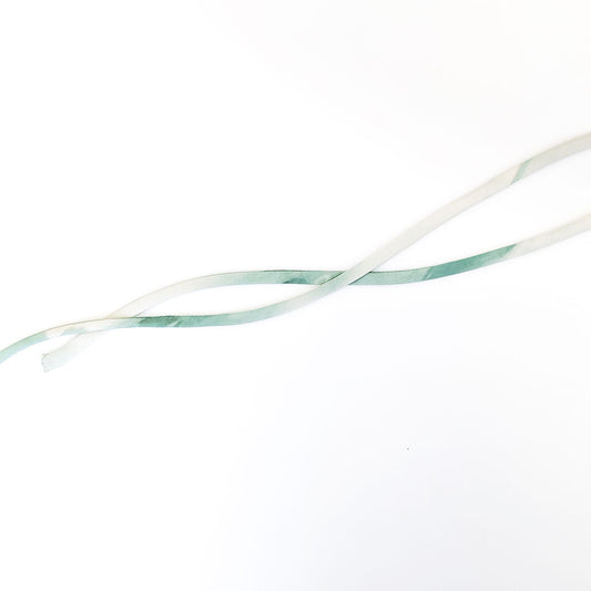 Narrow fabric tubes in cream and sage green showing turned spaghetti straps made using the rouleau method on white background