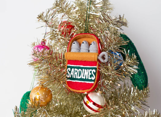 Grainline Studio felt sardines can ornament with three felt fish, hanging on gold tinsel Christmas tree with colorful baubles