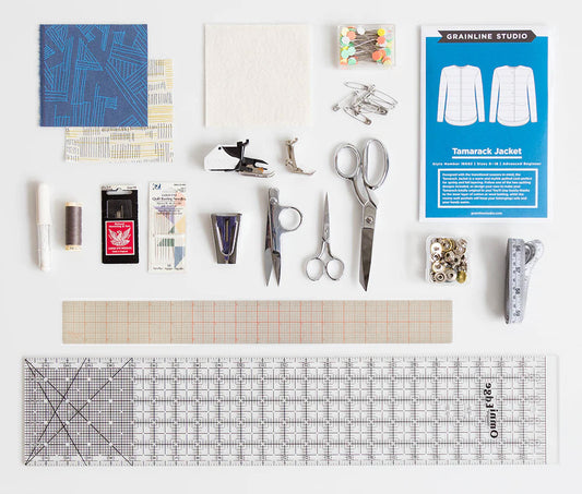 Tamarack Jacket sewing supplies flatlay with pattern envelope, fabric swatches, scissors, thread, needles, and measuring tools