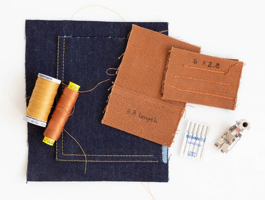 Thayer Jacket topstitching supplies: navy denim sample, Gutermann thread spools, brown fabric test pieces, and Schmetz needles
