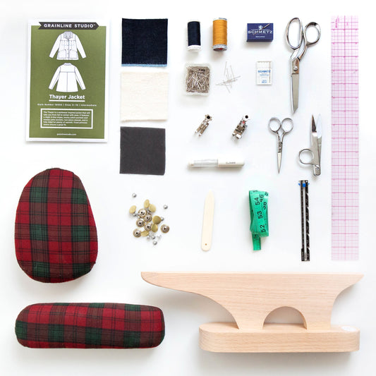 Thayer Jacket pattern envelope with supplies flat lay: fabric swatches, thread, scissors, pins, snaps, and pressing tools