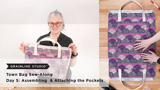 Grainline Studio Town Bag Sew-Along Day 5 thumbnail with purple wave print bag body and pocket assembly on wood surface