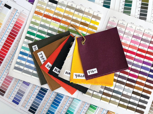 Fabric swatches labeled olive, toffee, orange, black, natural, yellow, and fig arranged on thread color charts for Town Kit