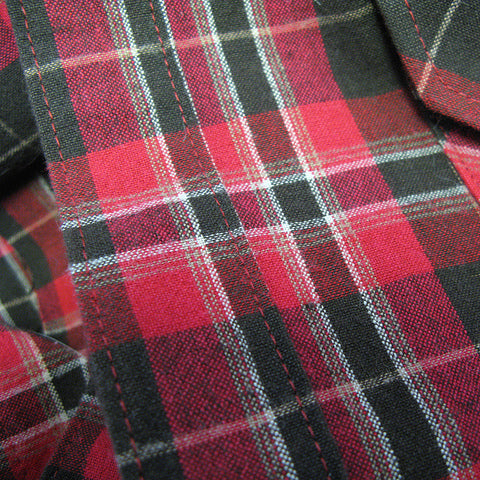 Close-up of red and charcoal flannel plaid shirt button band showing grid pattern with white stripes and woven texture
