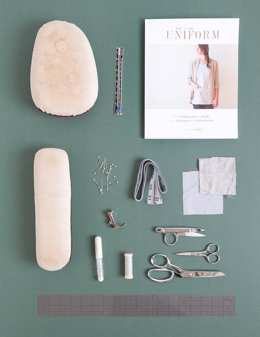 Knit and Sew Uniform book with tailor's ham, sleeve roll, fabric swatches, scissors, chalk pen, and ruler on sage green