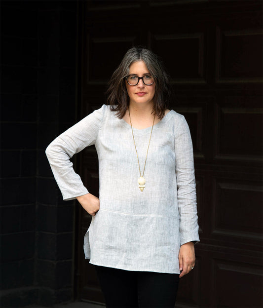 Uniform Tunic in light gray linen with long sleeves and scooped V-neckline, styled with gold pendant necklace and black pants